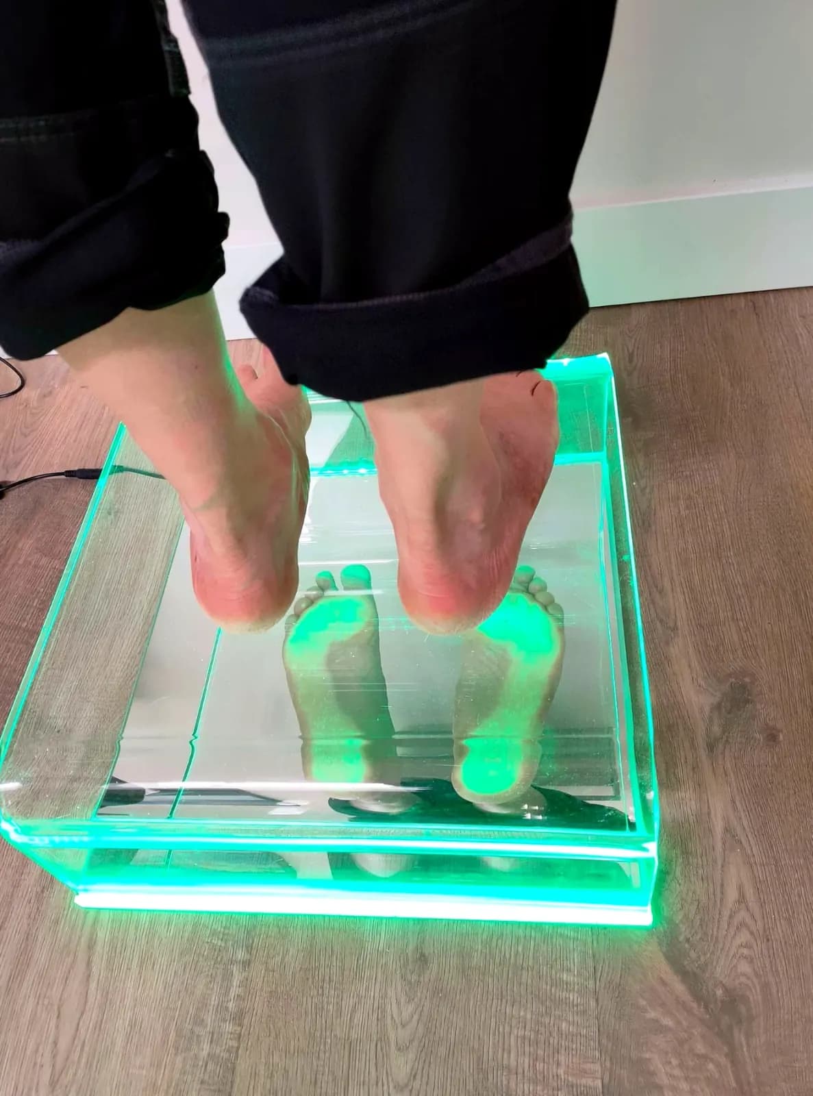 Twee blote voeten op de verlichte glasplaat van de podoscoop, waarop de drukverdeling onder de voet zichtbaar wordt